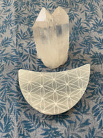 Load image into Gallery viewer, Alternate view. Beautiful selenite crescent moon, etched with the flower of life, can be used for cleansing and charging your crystals and jewelry because it dispels negative and unwanted energies. Selenite also promotes clarity of mind, opens the crown chakra, helps to access angelic energies and guidance from the higher realms. It brings peace and is a great stone to use while meditating or connecting spiritually and more. Approx. 3&quot;. Cost is $6.
