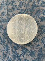 Load image into Gallery viewer, Beautiful selenite full moon charging plate, etched with the flower of life, can be used for cleansing and charging your crystals and jewelry because it dispels negative and unwanted energies. Selenite also promotes clarity of mind, opens the crown chakra, helps to access angelic energies and guidance from the higher realms. It brings peace and is a great stone to use while meditating or connecting spiritually and more. Approx. 3&quot;. Cost is $10. 
