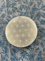 Load image into Gallery viewer, Beautiful selenite full moon charging plate, etched with the flower of life, can be used for cleansing and charging your crystals and jewelry because it dispels negative and unwanted energies. Selenite also promotes clarity of mind, opens the crown chakra, helps to access angelic energies and guidance from the higher realms. It brings peace and is a great stone to use while meditating or connecting spiritually and more. Approx. 3&quot;. Cost is $10. 
