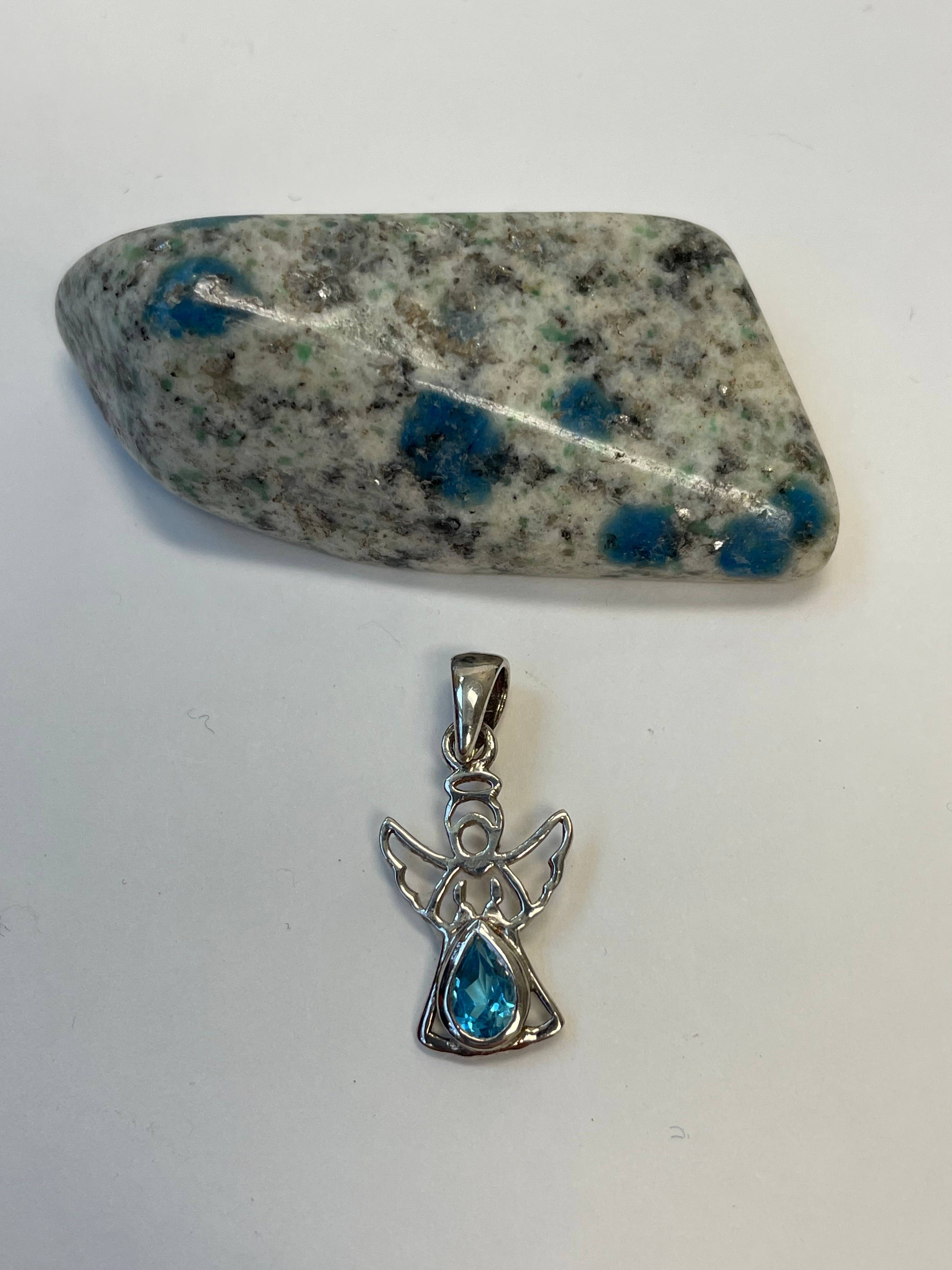 Alternate view. Dainty sterling silver angel pendant with stunning teardrop blue topaz. Blue topaz soothes & relaxes, is a stone of love and manifestation, verbal communication, emotional support and more. The angel reminds us that we are being watched over, always! Pendant is approximately 1" long. Cost is $18.00.