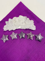Load image into Gallery viewer, View of several lepidolite stars. This lovely little Lepidolite star can be used for meditation, healing, for your altar, on your computer to clear EMRs, or as décor for any room in your home or office. Easy to slip right into your pocket so you can take the energy of lepidolite everywhere you go. Approximately 1¼&quot;. Cost is $6 for one star. 
