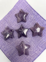 Load image into Gallery viewer, Another view of several lepidolite stars. This lovely little Lepidolite star can be used for meditation, healing, for your altar, on your computer to clear EMRs, or as décor for any room in your home or office. Easy to slip right into your pocket so you can take the energy of lepidolite everywhere you go. Approximately 1¼&quot;. Cost is $6 for one star. 
