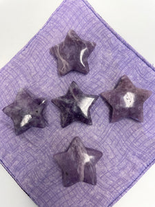 View of several lepidolite stars. This lovely little Lepidolite star can be used for meditation, healing, for your altar, on your computer to clear EMRs, or as décor for any room in your home or office. Easy to slip right into your pocket so you have the energy of lepidolite everywhere you go. Approximately 1¼". Cost is $6 for one star. 