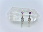 Load image into Gallery viewer, Round faceted amethyst gemstones are set in sterling silver (one in each earring) with long sterling feathers dangling below them. These have wires, not posts and are approximately 2&quot; long.
