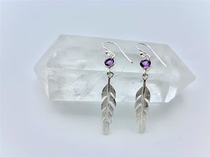 Round faceted amethyst gemstones are set in sterling silver (one in each earring) with long sterling feathers dangling below them. These have wires, not posts and are approximately 2" long.
