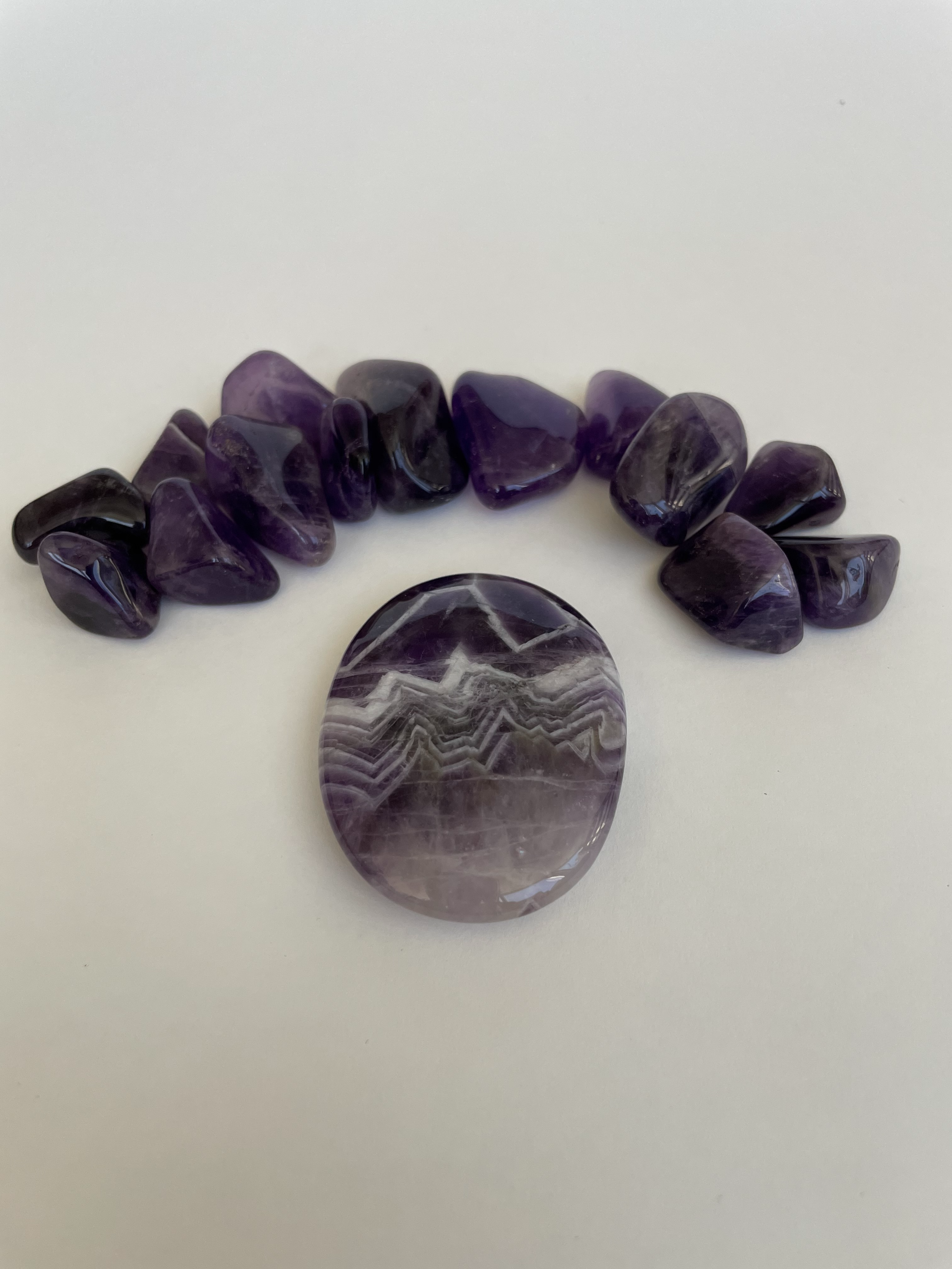 Love the banding on this palm stone.  Beautiful amethyst palm stone can be used for meditation, healing,  on your altar or as a décor item.  Amethyst, one of the most spiritual gemstones, heals, cleanses & calms, allowing you to reach meditative & higher consciousness levels more easily. It also helps to dispel negative emotional states and more. Chevron amethyst is a combination of amethyst and white quartz and when you add the quartz you get additional qualities. Approx. 2" long. Cost is $12.