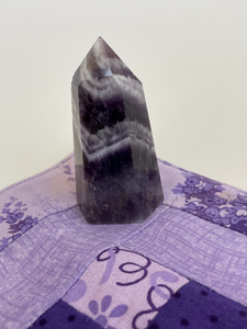 Alternate view. Chevron amethyst tower with the coolest banding for your altar, for healing or as décor for any room in your home or office. Amethyst, one of the most spiritual gemstones, heals, cleanses & calms, allowing you to reach meditative & higher consciousness levels more easily. It also helps to dispel negative emotional states and more. Chevron amethyst is a combination of amethyst and white quartz and when you add the quartz you get additional qualities. Approx. 2¼" long. Cost is $13.20.