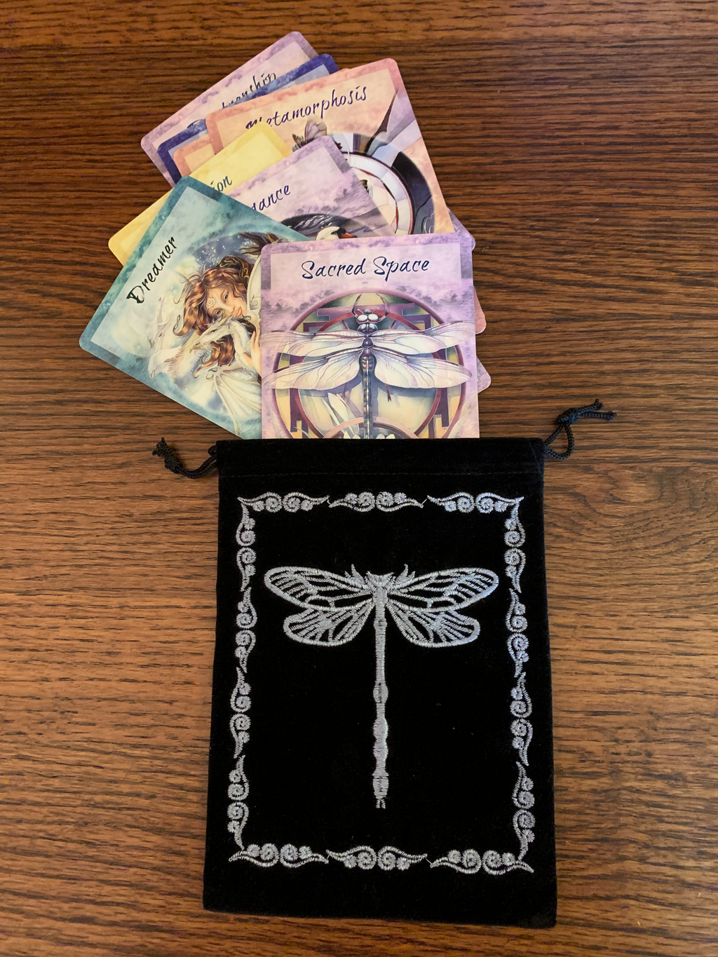 Lovely oracle/tarot deck bag with drawstrings for closure. It is black faux velvet with a light blue colored dragonfly embroidered on it with a border around it. This 7"x5" bag can fit most any deck, but is best suited for larger decks (e.g. Medicine Cards). It can also be used to hold and protect large crystals or other precious items. Cost is $7.50