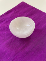 Load image into Gallery viewer, Alternate view. If you look closely, you can see the sparkles in this beautiful carved selenite bowl. It can be used for cleansing and charging your crystals and jewelry because it dispels negative and unwanted energies. Selenite also promotes clarity of mind, opens the crown chakra, helps to access angelic energies and guidance from the higher realms. It brings peace and is a great stone to use while meditating or connecting spiritually and more. The bowls are approximately 2¾&quot;-3&quot; in diameter. Cost is $12.

